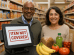 "African American man and Hispanic woman standing at a grocery store checkout with OTC card declined — register shows 'Item Not Covered' as they attempt to purchase healthy food."
